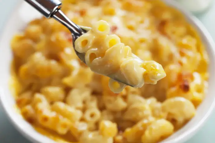Une cuillère de mac and cheese crémeux et doré, prêt à être dégusté.